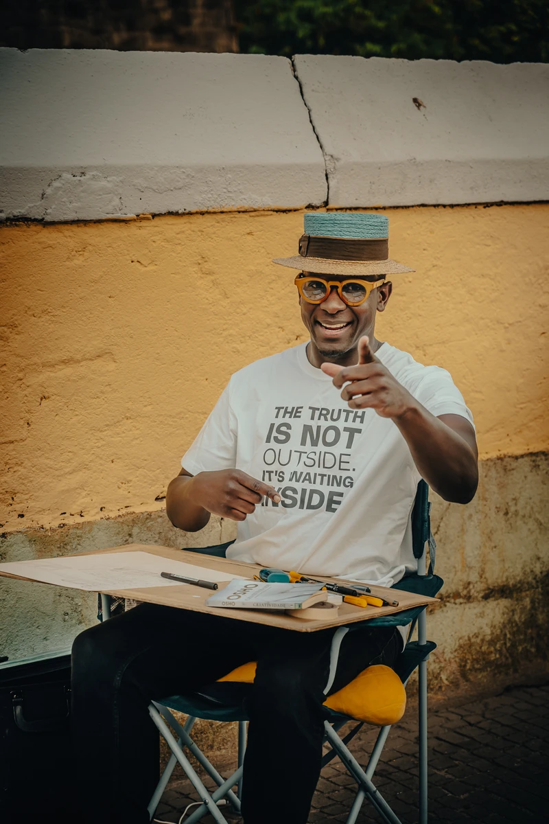 Gaspar Silva smiling at his street art table in Porto.